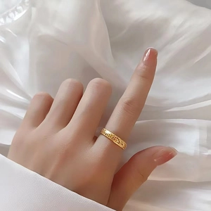 Détail d'une bague en titane doré avec motif d'écailles sur fond en soie douce