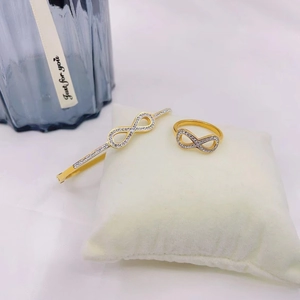 18K gold plated infinity jewelry set with sparkling crystals on white velvet pillow