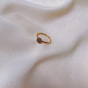 Minimalist 18K gold titanium steel ring with Fu character on white silk fabric