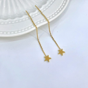 Close-up of gold star threader earrings with long tassels on a white ceramic tray