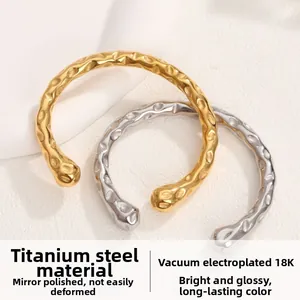 Dettaglio di bracciali aperti in acciaio inossidabile oro 18K e argento con trama martellata