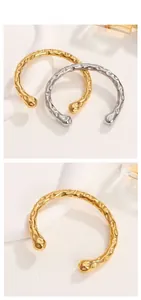 Dettaglio della trama martellata dei bracciali rigidi aperti in oro 18K e argento