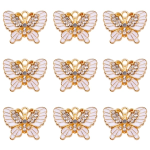 Detail of nine white enamel butterfly pendants with sparkling rhinestones for DIY jewelry