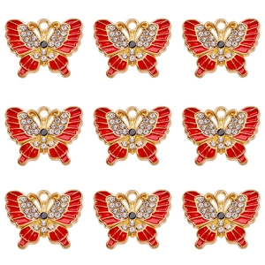 Detailed view of nine gold alloy butterfly pendants with red enamel and sparkling crystals