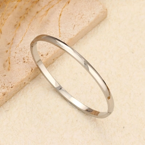 Minimalistische gepolijste roestvrijstalen bangle armband in zilver op natuursteen decor