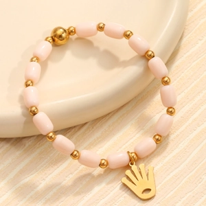 Bracelet en quartz rose avec accents dorés et pendentif main sur plateau céramique