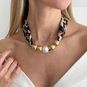 Detail of leopard print scarf necklace with gold beads and a large white pearl pendant