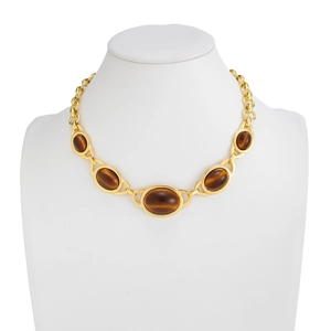 Detail van vintage gouden ketting met vijf ovale tijgeroogstenen op een etalagepop
