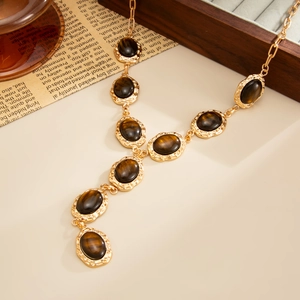 Detailopname van de gouden retro ketting met tijgeroog harsstenen en grove schakels