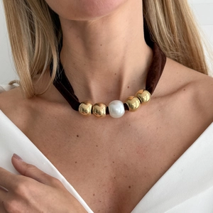 Close-up of leopard print scarf necklace with gold beads and a pearl on a model