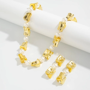 Detailopname van gouden geometrische accenten en witte parels op de ketting en oorbellen