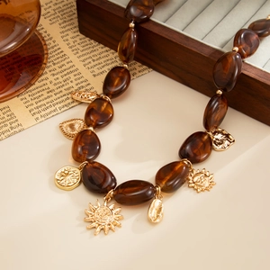 Detailopname van boho amberkleurige kralen en vintage gouden hangers met zonreliëf
