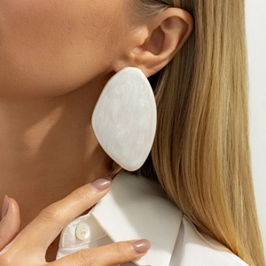 Detail of a large oval pearl-textured earring with gold metal frame on a model