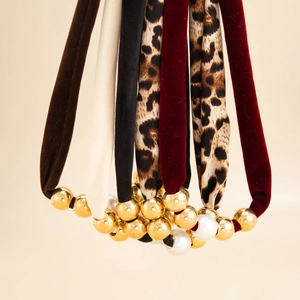 Close-up of leopard print and velvet scarf hair ties with gold and pearl bead accents