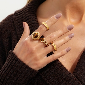 Vintage-Ring-Set aus Gold mit Tigerauge und Lavatextur getragen über braunem Strickpullover