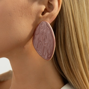 Macro view of teardrop earrings with pink marble texture and gold metallic edging