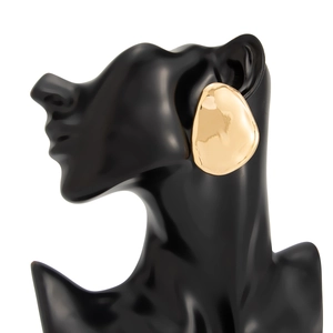 Macro detail of large gold-tone irregular geometric stud earring with hammered texture