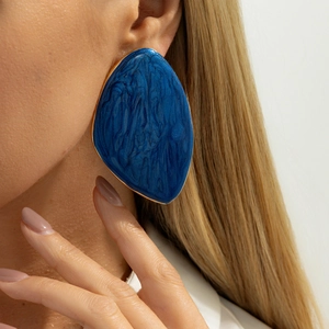 Detail of dark blue enamel geometric earrings with gold trim worn by a model