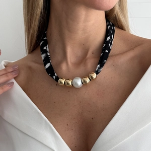 Detail van de luipaard sjaal ketting met gouden kralen en een grote witte parel