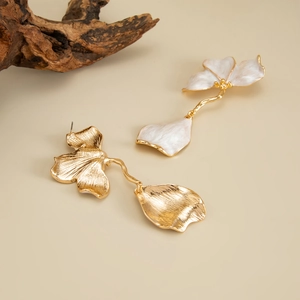 Détail de boucles d'oreilles florales avec pétales en métal doré et émail blanc