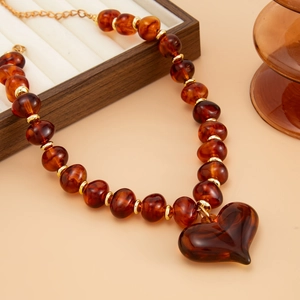 Detail van vintage ketting met barnsteenkleurige kralen, grote harthanger en gouden accenten