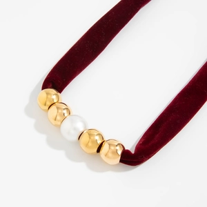 Close-up of vintage burgundy velvet knot necklace with gold beads and white pearls