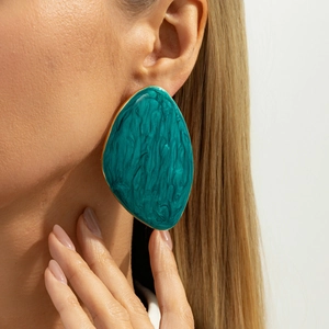 Close-up of chunky gold-edged oval earrings with emerald marble resin inlay on model