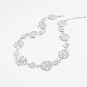 Macro shot of silver hammer-textured irregular circular discs and adjustable chain link