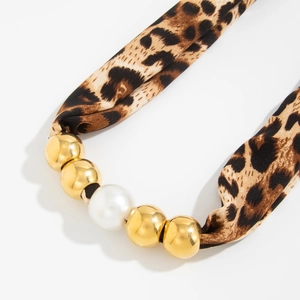 Detail of leopard print fabric scarf necklace with gold beads and white pearl accent