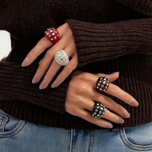 Detail showing resin rivet rings in amber and black on hand for a bohemian punk style