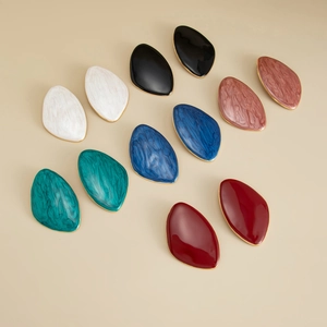 Macro shot of assorted asymmetric resin teardrop earrings with gold-plated metallic borders