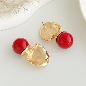 Gros plan détaillé de boucles d'oreilles dorées martelées avec de grandes perles rouges