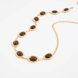Detailed view of vintage gold body chain with oval faux tiger eye stones and floral metalwork