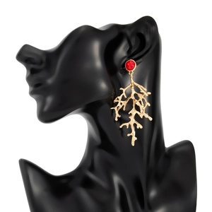Detail von korallenförmigen Goldohrringen mit rotem Stein auf einem schwarzen Model