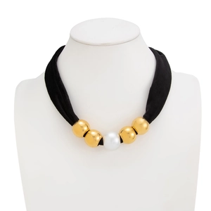 Detail of a black velvet choker necklace with gold metallic beads and a white faux pearl