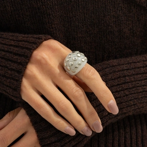 Detailed view of wide white resin ring with silver metal studs on model hand