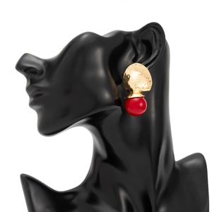 Detail eines Vintage-Ohrrings mit goldener Hammerschlag-Scheibe und großer roter Perle
