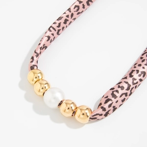 Detail van roze luipaardprint zijden lint ketting met gouden kralen en witte parel
