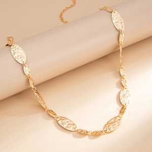 Macro view of golden irregular hammered oval discs on an adjustable metal waist chain