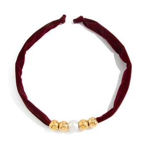 Detail of burgundy velvet choker with gold metal beads and a central white faux pearl