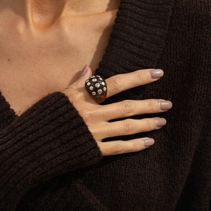 Close-up of tortoise resin ring with silver studs worn over a brown knit sweater