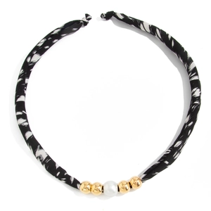 Detail van luipaardprint stoffen ketting met gouden kralen en een centrale parel-accent