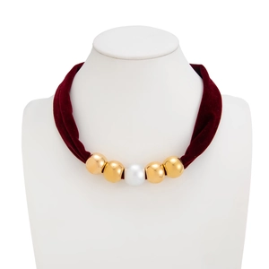 Detail of burgundy velvet choker with gold beads and white pearl on a white neck model