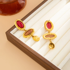 Détail macro de boucles d'oreilles vintage dorées avec résine sur un présentoir en bois