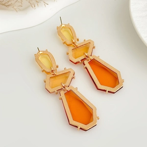 Détail de boucles d'oreilles géométriques à trois niveaux en résine orange et métal doré