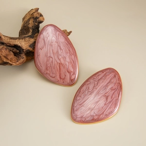 Detail of irregular resin stone earrings with gold metal edges on natural wood background