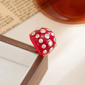 Close-up of red resin ring with silver studs displayed on a vintage jewelry box edge