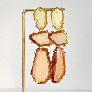 Détail de boucles d'oreilles géométriques en résine ambrée avec incrustation métal
