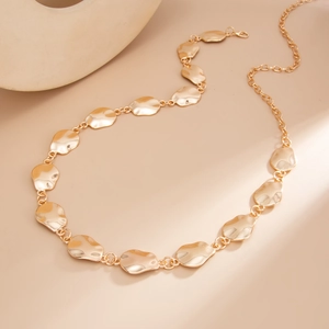 Close-up of golden irregular geometric metal link chain with polished mirror finish texture