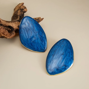 Detail of dark blue marble enamel drop earrings with elegant polished gold-tone metal edges